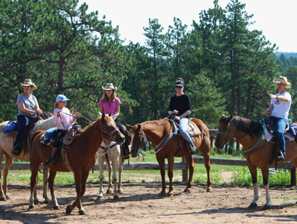 A solo female rider on horseback pauses to take in the breathtaking views at Sundance Trail Guest Ranch during her Colorado dude ranch vacation.