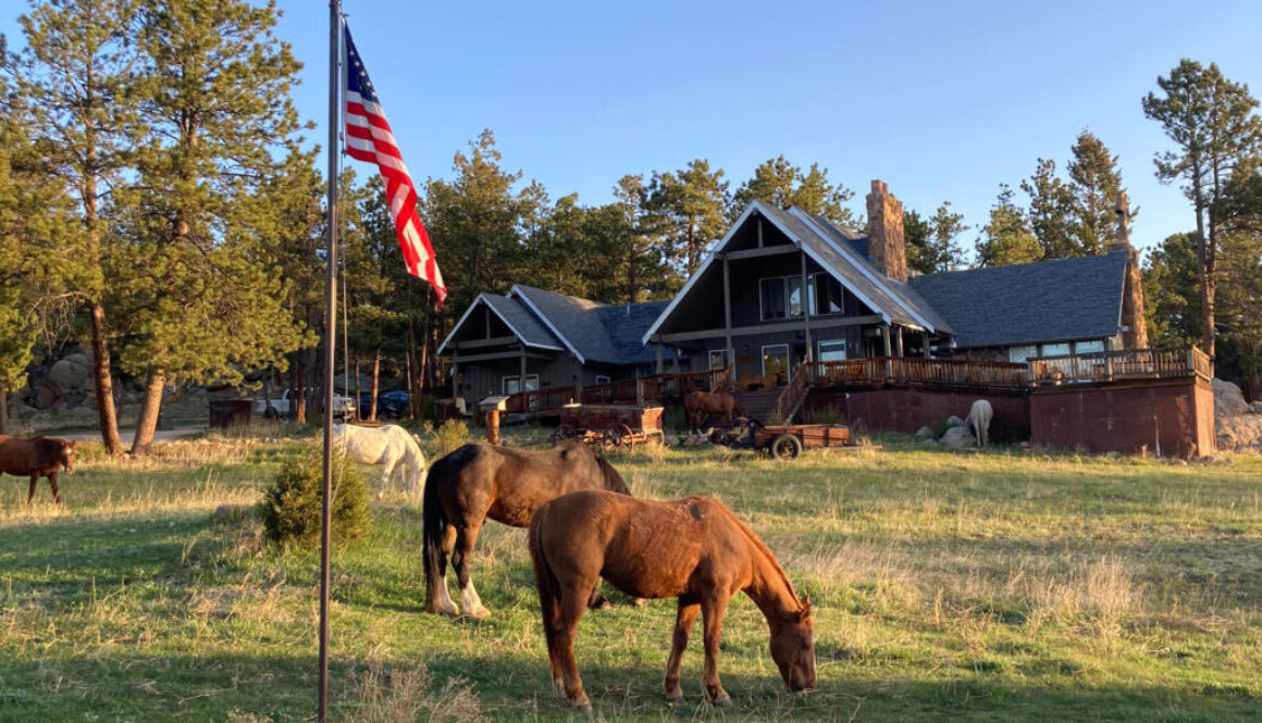 lodge with american flag and horses in foreground